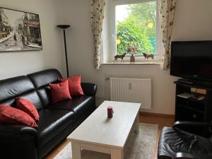 Sala de estar con sofá de cuero negro y mesa de centro en Ferienwohnung im Grünen mit Terrasse WF en Herdecke