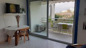 een kamer met een tafel en een balkon met een televisie bij appartement vue mer résidence les terrasses de la mer in La Grande-Motte