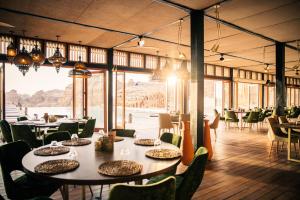 a dining room with tables and chairs and large windows at Our Habitas AlUla in AlUla