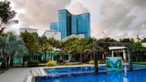 a hotel with a swimming pool in front of a tall building at Twin Palms Resort in Sihanoukville