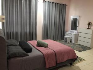 馬六甲的住宿－Homestay Ruma Melaka，一间卧室配有一张带粉色毯子的床和一台电视。