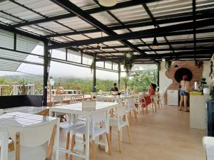 ein Restaurant mit weißen Tischen und weißen Stühlen in der Unterkunft Papa Garden Khaokho in Khao Kho