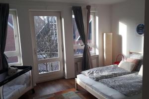 een slaapkamer met 2 bedden en een deur met ramen bij Nordhörnchen! Sehr zentral, trotzdem ruhig! in Nordhorn