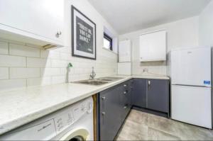 a kitchen with a white refrigerator and a dishwasher at Light & Airy Oasis in South Norwood