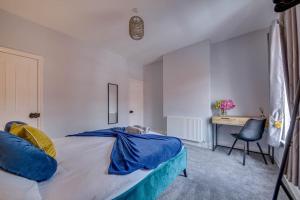 a bedroom with a bed with blue sheets and a desk at Liquorice Lodge- 2 bed & parking in Castleford