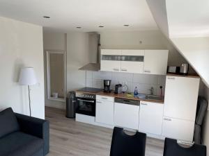 a kitchen with white cabinets and a couch in a room at Seaside-Amrum-15 in Norddorf
