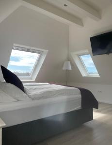 ein weißes Schlafzimmer mit einem Bett und einem Fenster in der Unterkunft Seaside Amrum 17 in Norddorf