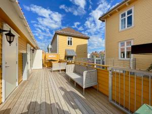 a wooden deck with chairs and a house at Vibrant apartment on bustling street, above a restaurant Perfect for tourists, in Stavanger