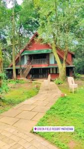 a red house with two chairs in front of it at Greenfield Resort, Matheran in Matheran