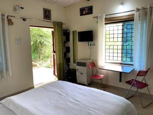 a bedroom with a bed and a desk and two chairs at Sattva Farmstay in Bangalore