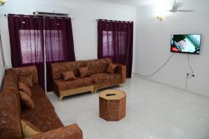 - un salon avec des canapés bruns et une télévision dans l'établissement New Furnished Apartment, à Djibouti