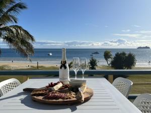 einen Tisch mit einer Flasche Wein und Gläsern am Strand in der Unterkunft Paradise Palms Tangalooma in Tangalooma