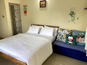 a bedroom with a large bed and a blue couch at Sattva Farmstay in Bangalore