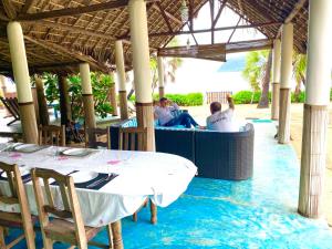 um grupo de pessoas sentadas numa mesa sob um pavilhão em Mitsio Paradise - Hotel privatif en pension complète em Nosy Mitsio