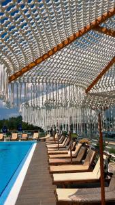 uma piscina com cadeiras e lustres pendurados sobre uma piscina em Misk Hotel & Resort em Tirana