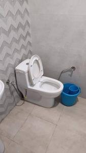 a bathroom with a toilet with the seat up and a bucket at 85 The Ganges 2 BHK Apartment for Homestay in Rishīkesh