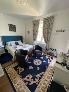 1 Schlafzimmer mit einem Bett, 2 Stühlen und einem Teppich in der Unterkunft Vue du Château d'Excideuil in Excideuil