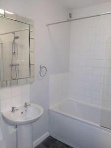 a white bathroom with a sink and a bath tub at Parkside Apartment Normanton in Wakefield
