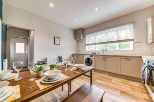 a kitchen with a wooden table with wine glasses at The Collier's Rest: 3 bed home in South Yorks with parking & garden. in Barnsley