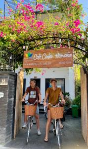 twee vrouwen die fietsen voor een restaurant bij Coto Center Homestay in Dao Co To
