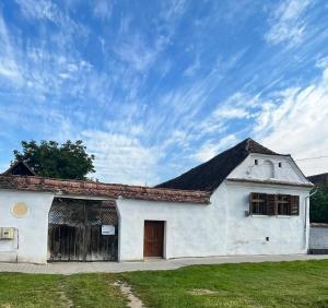 un antiguo edificio blanco con techo negro en Haus Rether - Transylvanian Guesthouse en Buneşti