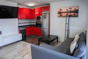 a living room with a couch and a kitchen with red cabinets at La bona vida Vitoria in Arriaga