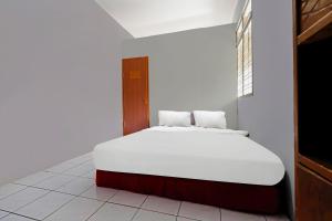 a white bed in a room with a window at OYO Life 92694 Kost Nino in Bandung