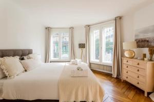 a white bedroom with a large bed and windows at Spacious, Central & Historic Getaway - 5 Star Location in Paris