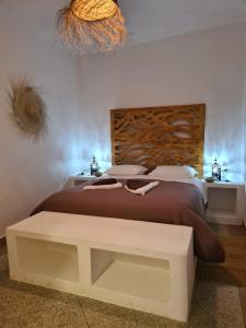 a bedroom with a bed with a bench next to it at La Maison des Vagues in Sidi Kaouki