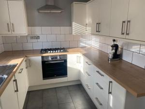 a kitchen with white cabinets and a stove top oven at Sleep up to 14 - Doncaster central in Doncaster