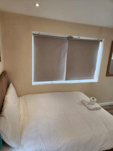 a bedroom with a white bed with a window at Beautiful private en-suite room with its own entry in Bexleyheath