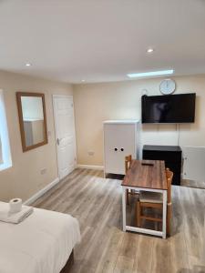 a room with a bed and a table and a tv at Beautiful private en-suite room with its own entry in Bexleyheath