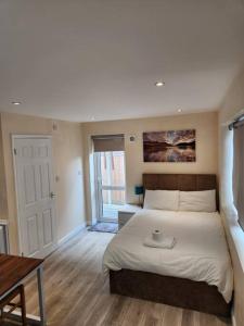 a bedroom with a large bed and a table at Beautiful private en-suite room with its own entry in Bexleyheath