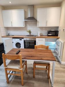 a kitchen with a wooden table and chairs and a microwave at Beautiful private en-suite room with its own entry in Bexleyheath