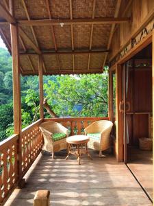 eine Veranda mit Korbstühlen und einem Tisch in der Unterkunft Rambai Tree Jungle Lodges in Bukit Lawang
