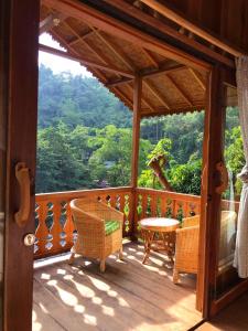 a wooden porch with a table and chairs on it at Rambai Tree Jungle Lodges in Bukit Lawang