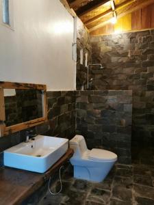a bathroom with a white toilet and a sink at Rambai Tree Jungle Lodges in Bukit Lawang