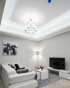 a white living room with a white couch and a tv at Seef manzil in Seef