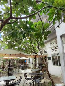 Un patio al aire libre con mesas, sillas y sombrillas. en Bestow Boutique Hotel, en Kuala Lumpur