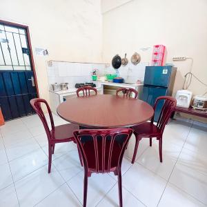 una cucina con tavolo in legno e sedie rosse di VILLA BUKIT MAS BERASTAGI DEPAN MIKIE FUNLAND a Berastagi