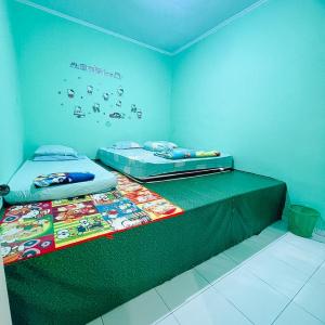 two twin beds in a room with blue walls at VILLA BUKIT MAS BERASTAGI DEPAN MIKIE FUNLAND in Berastagi