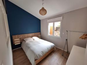 1 dormitorio con cama y pared azul en Bienvenue chez toi - TV, WiFi, en Castanet-Tolosan