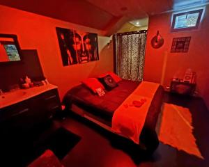 een rode slaapkamer met een bed en een wastafel bij Love room, Les nuitées secrètes de Rouen in Darnétal
