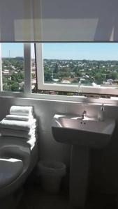 baño con aseo y lavabo y ventana en Hotel Aranjuez, en Chillán