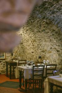 a restaurant with tables and chairs and a stone wall at Agriturismo Ferdy in Lenna