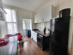 een keuken met een zwarte koelkast en een tafel bij Remarkable 1-Bed House the entire first floor in Westcliff On Sea