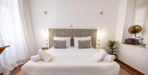een slaapkamer met een groot bed met witte lakens en kussens bij Apeiron Acropolis Suites in Athene