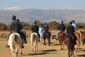 a group of people riding horses on a field at Soetgeluk Farm Cottage in Hekpoort