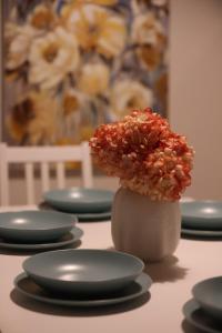uma mesa coberta com pratos e um vaso cheio de flores em Comfort and Convenience flat 4 dad's court em St. Paul's Bay