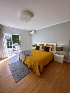 um quarto com uma cama grande e um cobertor amarelo em Moro's Friends House - Cascais em Cascais